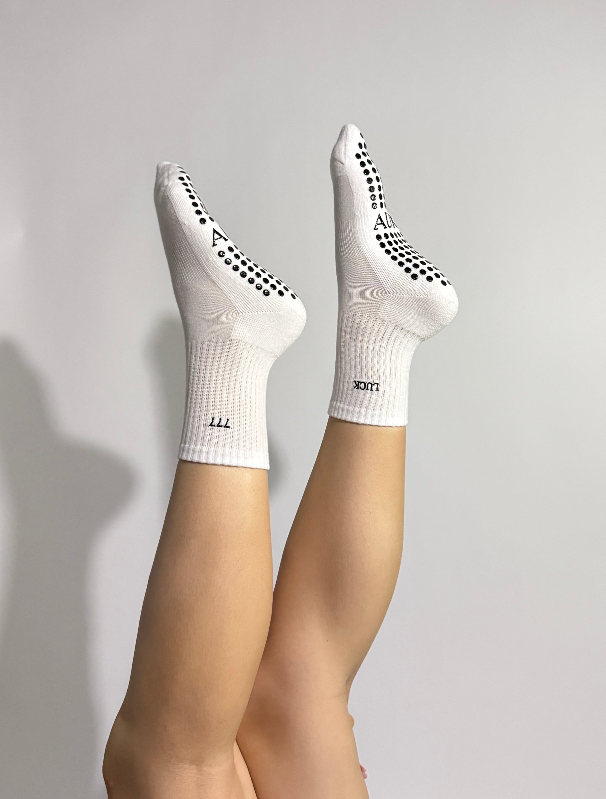 White 777 non-slip socks worn by a person during a Pilates exercise 